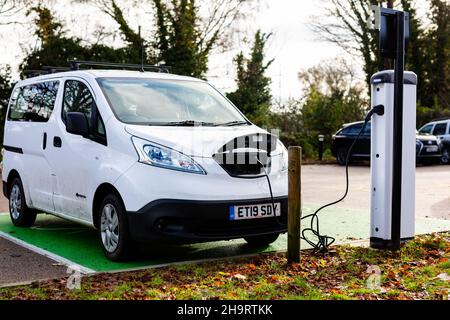 Woodbridge Suffolk UK Novembre 28 2021: Nissan e-NV200 furgone elettrico carica alla presa di carica in un parcheggio pubblico a Suffolk, Regno Unito Foto Stock