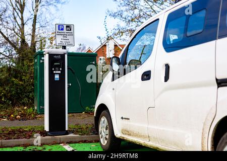 Woodbridge Suffolk UK Novembre 28 2021: Nissan e-NV200 furgone elettrico carica alla presa di carica in un parcheggio pubblico a Suffolk, Regno Unito Foto Stock