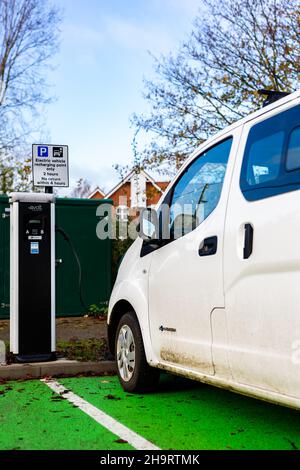 Woodbridge Suffolk UK Novembre 28 2021: Nissan e-NV200 furgone elettrico carica alla presa di carica in un parcheggio pubblico a Suffolk, Regno Unito Foto Stock