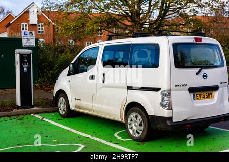 Woodbridge Suffolk UK Novembre 28 2021: Nissan e-NV200 furgone elettrico carica alla presa di carica in un parcheggio pubblico a Suffolk, Regno Unito Foto Stock