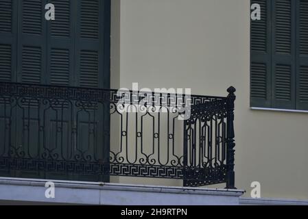 Facciata antica casa neoclassica con persiane in legno di pino verde e una ringhiera artigianale in ferro battuto balcone a Nafplio, Grecia. Foto Stock