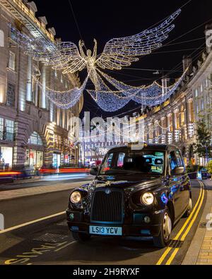 Londra, Regno Unito - Dicembre 2nd 2021: Taxi tradizionale parcheggiato in Regent Street a Londra, Regno Unito, con le belle luci di Natale. Foto Stock
