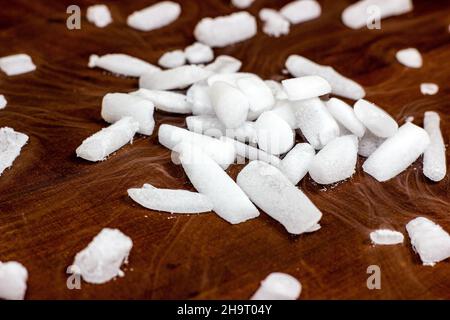 Ghiaccio secco fresco bianco (anidride carbonica congelata) con effetto fumo sullo sfondo di legno marrone scuro. Foto Stock