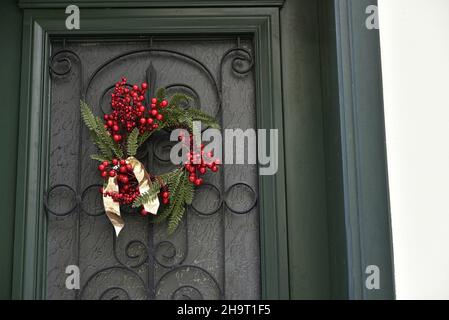 Casa neoclassica porta verde in legno con griglie in ferro artigianali e una festosa corona di Natale in edera a Nafplio, Grecia. Foto Stock