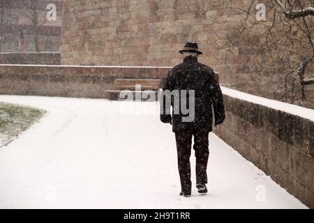 Vista posteriore di un maschio anziano che cammina su un sentiero innevato Foto Stock