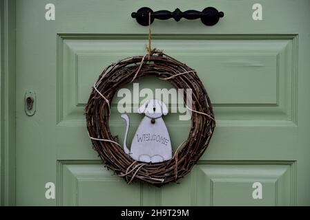 Tradizionale casa verde menta porta di legno con un antico manico di ottone e un cane wreath segno di benvenuto a Nafplio, Grecia. Foto Stock