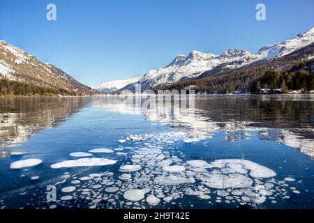 Bolle di metano intrappolate sotto il lago ghiacciato con paesaggio come sfondo Foto Stock