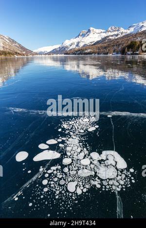 Bolle di metano intrappolate sotto il lago ghiacciato con paesaggio come sfondo Foto Stock