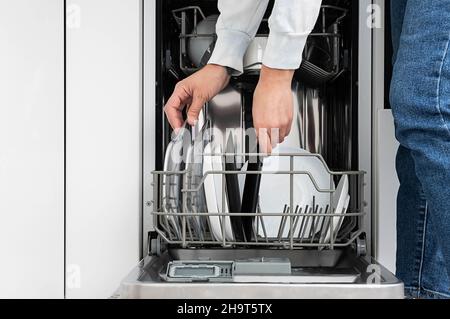 Donna che fa piatti in lavastoviglie a casa. Pulire le piastre dopo aver lavato la cucina moderna con lavastoviglie. Le faccende domestiche. Foto Stock