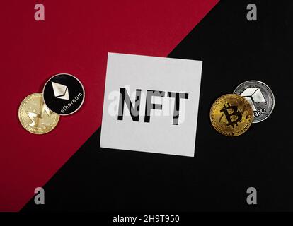 Acronimo NFT su carta nota su sfondo rosso e nero con monete di criptovaluta. Foto Stock