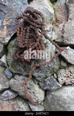 Una vecchia portachiavi arrugginita appesa a una recinzione in pietra. Foto Stock