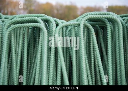 Una pila di barrette per-fabbricate con un rivestimento epossidico verde per la resistenza alla corrosione è pronta per l'installazione in un progetto di infrastruttura. Foto Stock