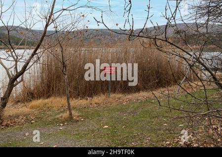 Cartello rosso di avvertimento sul lago: 'E' pericoloso e vietato entrare nel lago' (Göle girmek tehlikeli ve yasaktir in turco) Foto Stock