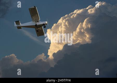 Piccolo aeroplano a motore singolo sullo sfondo del cielo nuvoloso. Foto Stock
