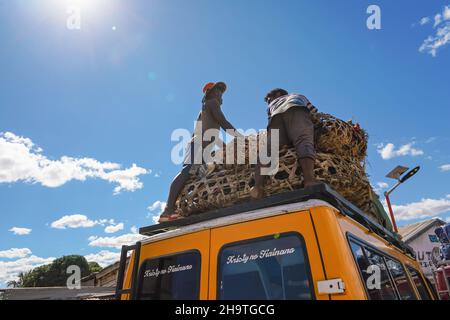 Ilakaka, Madagascar - 05 maggio 2019: Due sconosciuti uomini malgasci in piedi sul tetto dell'auto, organizzando polli in gabbie di paglia per il trasporto , view form belo Foto Stock