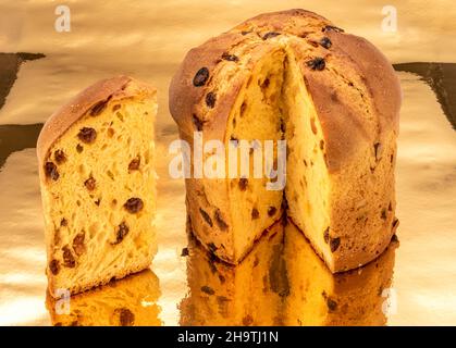 Torta Panettone tagliata a fette su sfondo dorato dove si riflette, classica torta di Natale italiana Foto Stock