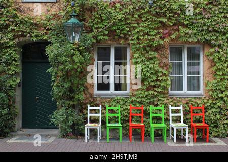 Boston ivy, super-riduttore giapponese (Parthenocissus tricuspidata), sedie colorate di fronte a una casa, Germania, bassa Sassonia, Hannover Foto Stock