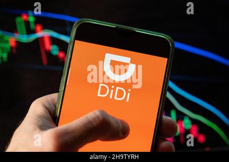 In questa illustrazione della foto la società cinese di ride-sharing, il logo Didi visto su uno smartphone con un grafico di indice di borsa economica sullo sfondo. Foto Stock