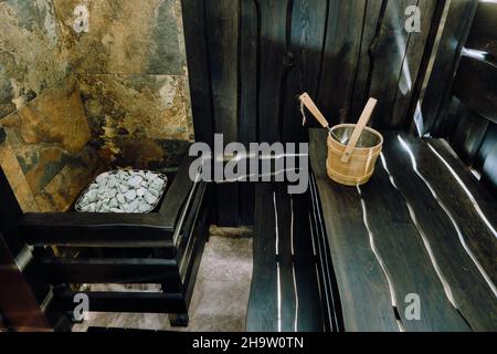 Secchio e mestolo in una sauna in legno. Accessori in legno nella sauna. Foto Stock