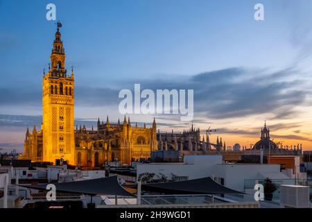 Vista al tramonto da un tetto che si affaccia su Siviglia, Spagna, con la Torre Giralda e la grande Cattedrale di Siviglia in vista sullo skyline della prima sera Foto Stock