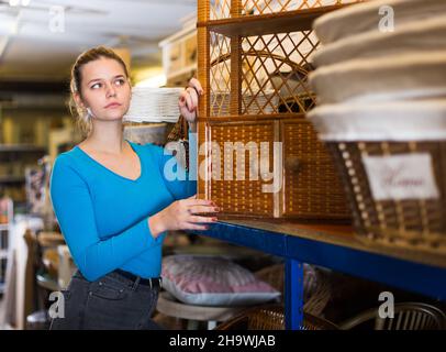 Giovane donna consumatore vicino vimini commode Foto Stock