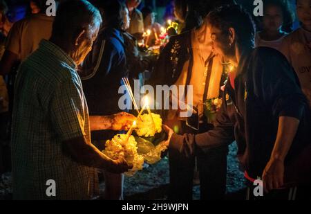 Accendendo candele per galleggiare sul fiume in un festival Loy Krathong nella Thailandia rurale Foto Stock