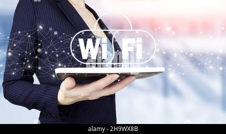 Free Wi-Fi rete tecnologia segnale concetto internet. Tenere il tablet bianco con ologramma digitale segno Wi Fi su sfondo sfocato chiaro. WIFI gratuito n Foto Stock