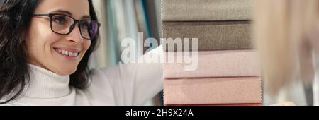 Venditore donna che mostra i campioni di tessuti dei clienti in negozio Foto Stock