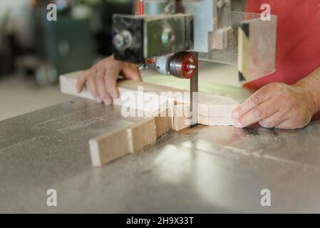 persona che taglia un asse di legno con una sega a nastro Foto Stock