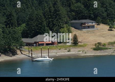 Case Familien con molo privato collegato con ponte e motoscafo osservato da nave mercantile container. Foto Stock