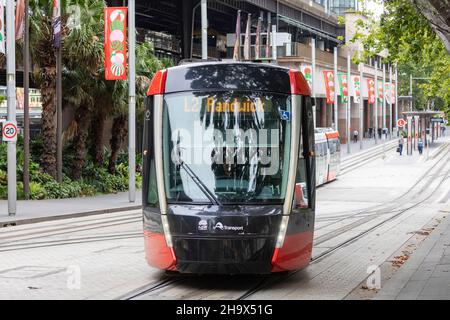 Il treno della ferrovia leggera di Sydney parte dalla stazione della ferrovia leggera di Circular Quay, la città di Sydney banner natalizi linea la strada, Sydney, Australia Foto Stock