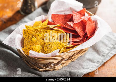 Triangolo di tortilla salato con aroma di barbabietola rossa e con semi di chia in ciotola su tavola di legno. Foto Stock