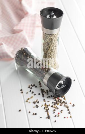 Macinacaffè e pepe intero su tavola bianca. Foto Stock
