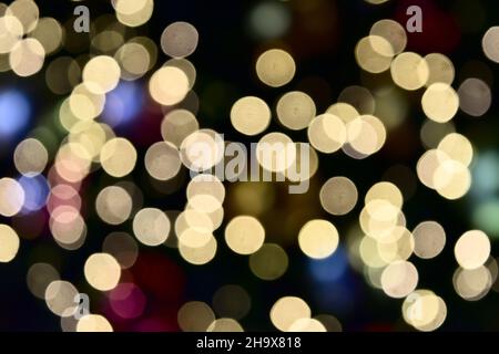 Bokeh da illuminazione interna, colorati cerchi di luce sparsi su viola con giallo con rosa e arancione su sfondo nero per la celebrazione Foto Stock