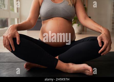 Donna caucasica madre incinta seduta su tappeto yoga esercizi di respirazione Foto Stock