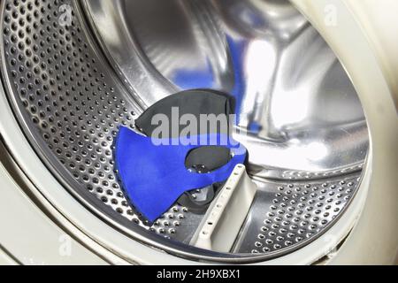 Due mascherine mediche di panno lavate si chiudono in un cesto vuoto della lavatrice Foto Stock