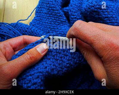 Mani che si accoccolano con lana blu Foto Stock