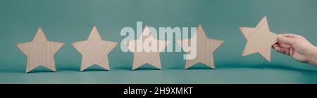 Cinque stelle su uno sfondo blu, mano mettere l'ultima stella in fila, valutazione Foto Stock