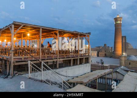 BUKHARA, UZBEKISTAN - 30 APRILE 2018: Vista serale di Mir-i-Arab Madrasa, minareto e moschea Kalan e una terrazza caffè a Bukhara, Uzbekistan Foto Stock