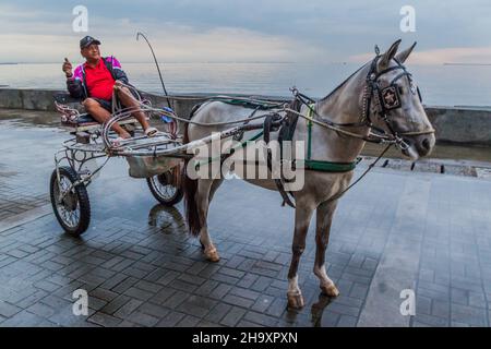 MANILA, FILIPPINE - 28 GENNAIO 2018: Carrozza di cavalli per i turisti sul mare nel distretto di Ermita a Manila, Filippine Foto Stock