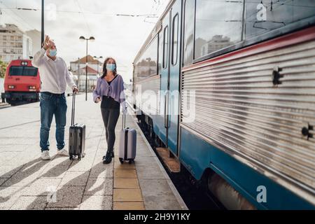 Turisti con valigie e maschere sulla piattaforma accanto al treno, Portogallo Foto Stock