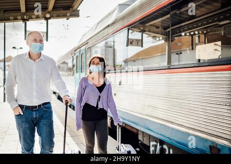 Turisti con valigie e maschere sulla piattaforma accanto al treno, Portogallo Foto Stock