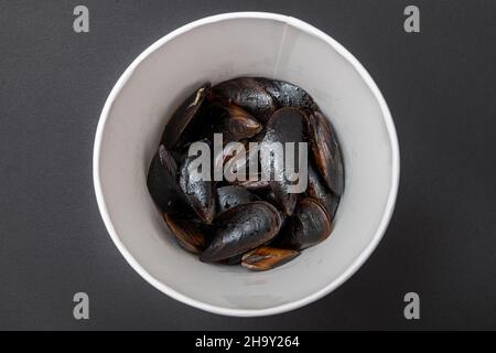 Cozze fresche ripiene in secchio su sfondo di pietra scura Foto Stock