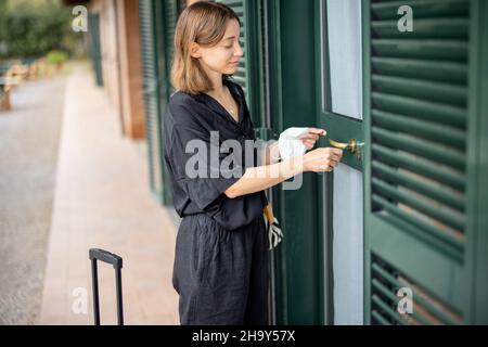 Ragazza in maschera medica con bagaglio andare in camera d'albergo Foto Stock