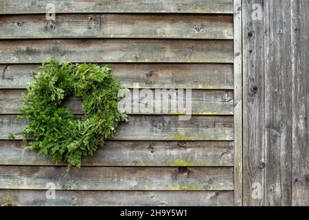 Una corona di Natale su un muro rustico fienile Foto Stock