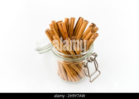 Bastoncini lunghi di alta qualità in cannella con clip per conservare il vaso in vetro isolato sul bianco. Vista ad angolo alto. Foto Stock