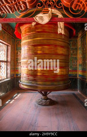 Una ruota di preghiera gigante che gira nel monastero di Guru Lhakhang dal Boudhanath Stupa a Kathmandu, Nepal. Foto Stock