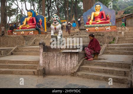 Una donna nepalese che vende lampade al burro all'ingresso del complesso del tempio di Swayambhunath a Kathmandu, Nepal. Foto Stock