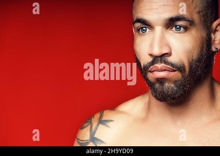 Faccia con una barba e un orecchino nell'orecchio di un uomo cubano primo piano. Ritratto da studio di un uomo brutale. Foto Stock