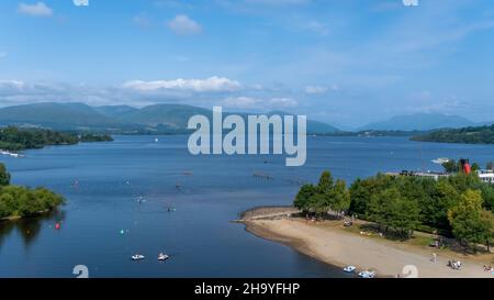 Ammira il Loch Lomond dalle coste di Lomond in una giornata estiva soleggiata in Scozia, con persone che partecipano agli sport acquatici, Balloch, Scozia Foto Stock